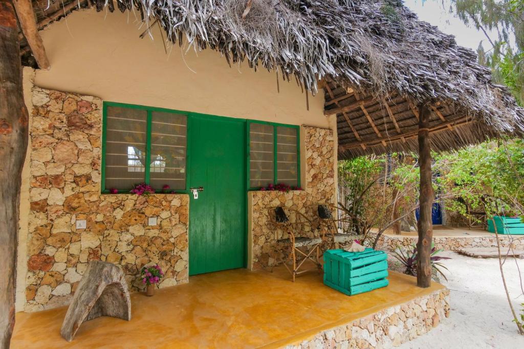 a house with a green door and a stone wall at Demani Lodge Zanzibar in Paje