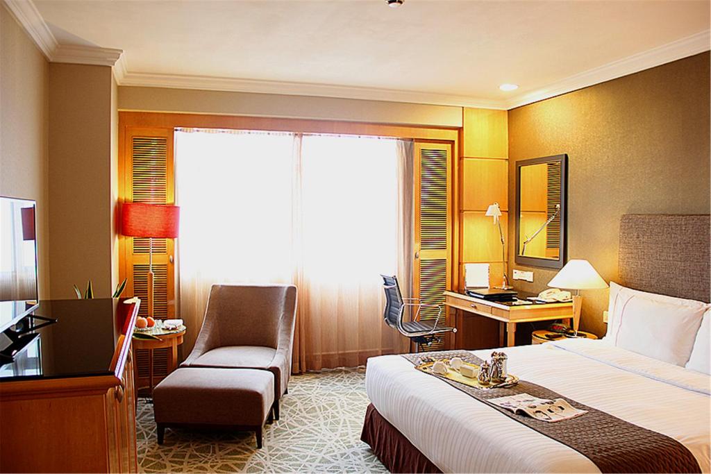 una camera d'albergo con letto, sedia e scrivania di Grand Park Wuxi a Wuxi