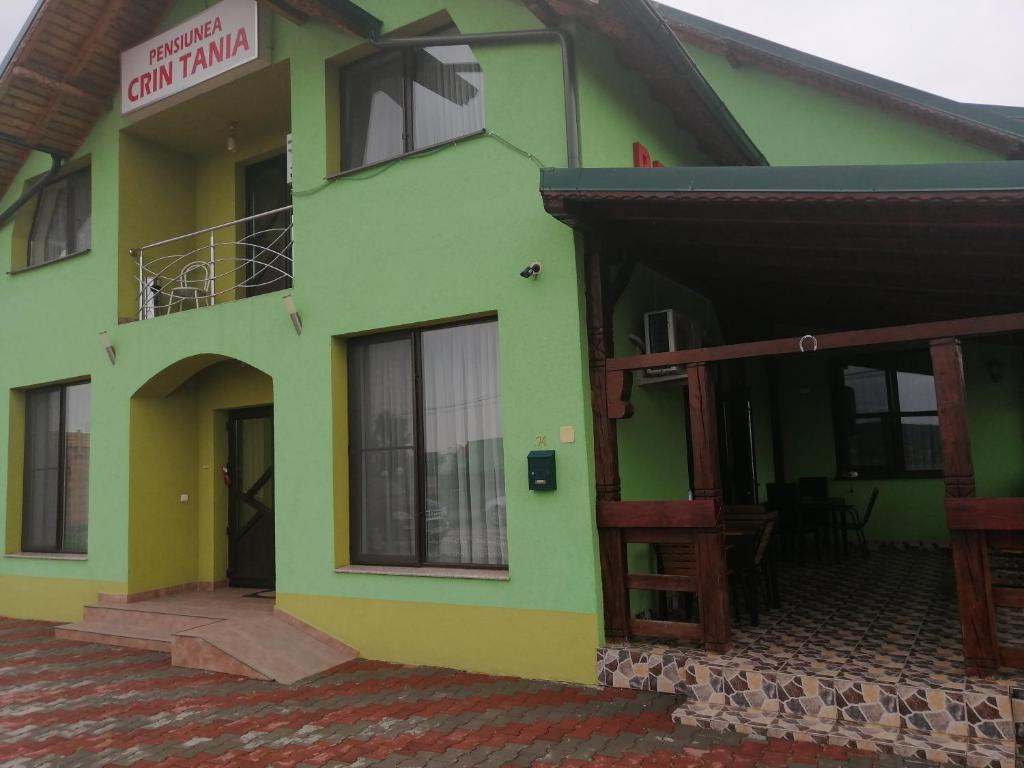 um edifício amarelo e verde com uma varanda em Pensiunea Crin-Tania em Mioveni