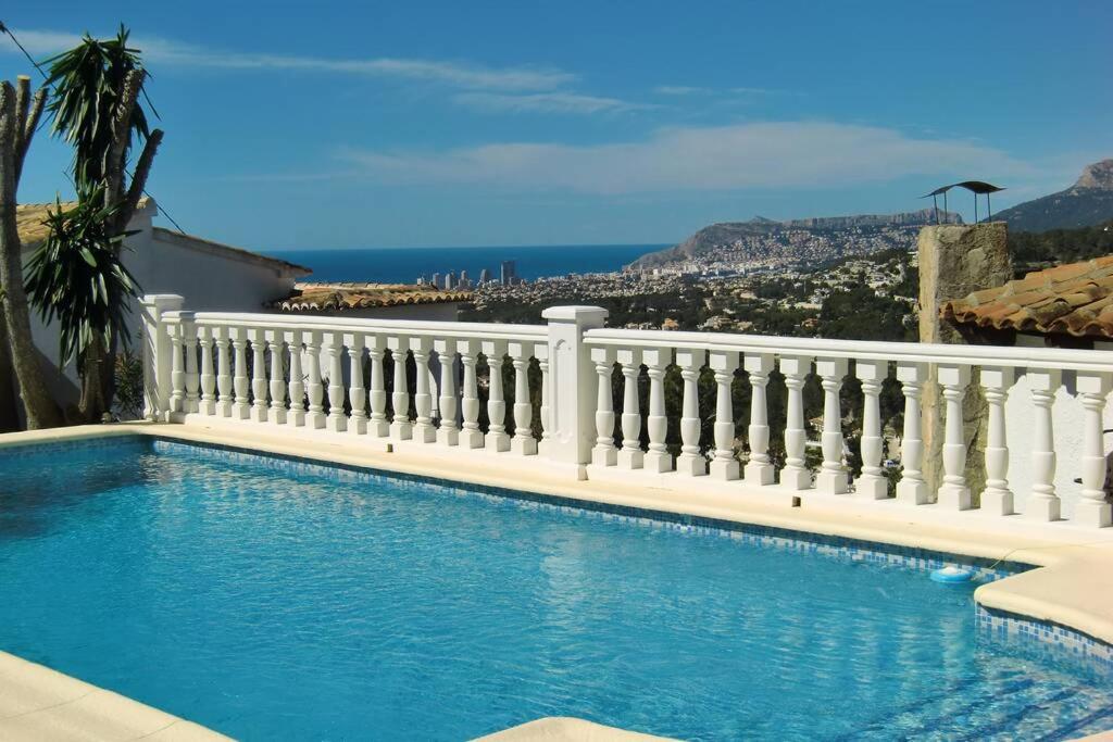 einen Pool mit einem weißen Zaun und dem Meer in der Unterkunft Casa León with private pool great view in Benissa