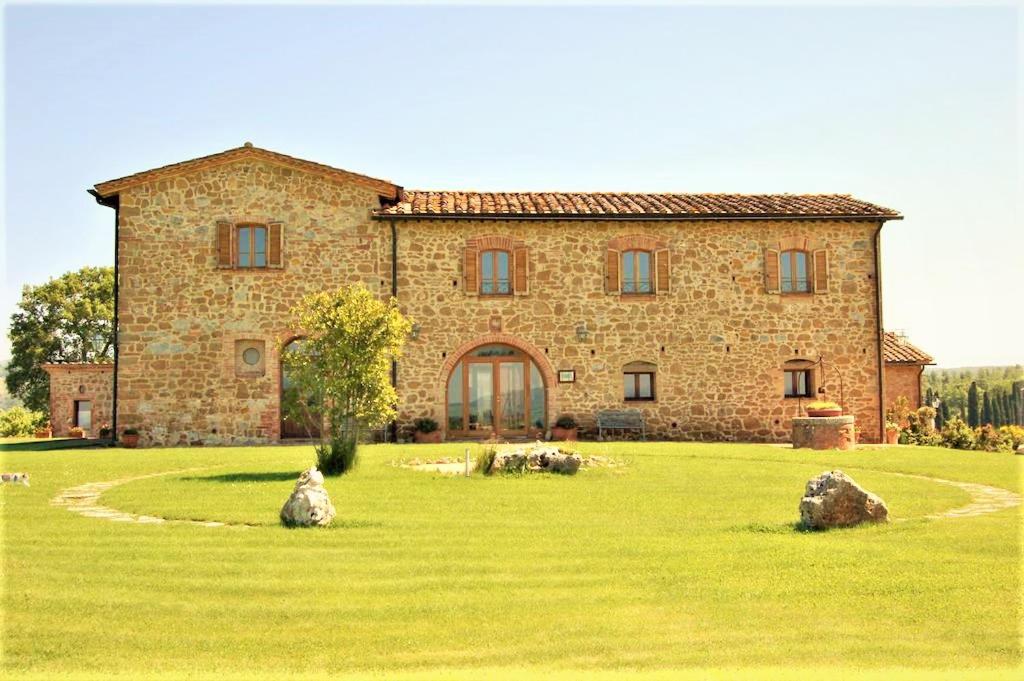 a large stone house in a field of grass at Locanda Vesuna in Pienza