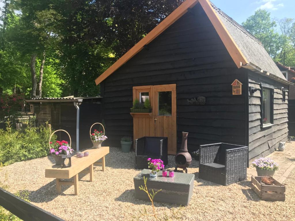 Un hangar noir avec un banc et des fleurs devant lui dans l'établissement Veluwse Bos en Heide Studio, à Otterlo