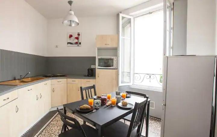 uma cozinha com uma mesa preta com cadeiras e um frigorífico em Appartement charmant dans le centre de Biarritz Dan 3ème étage em Biarritz