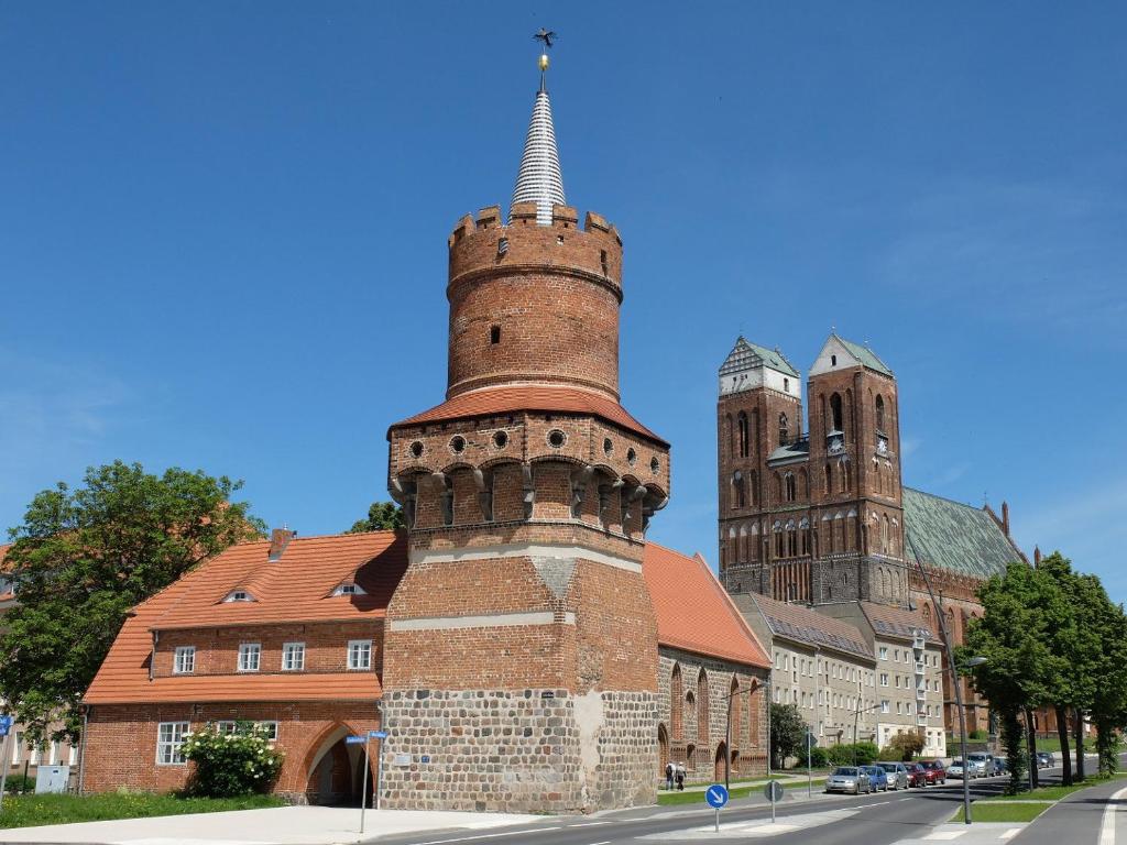 een bakstenen gebouw met een toren en een kerk bij Pension Mitteltorturm in Prenzlau