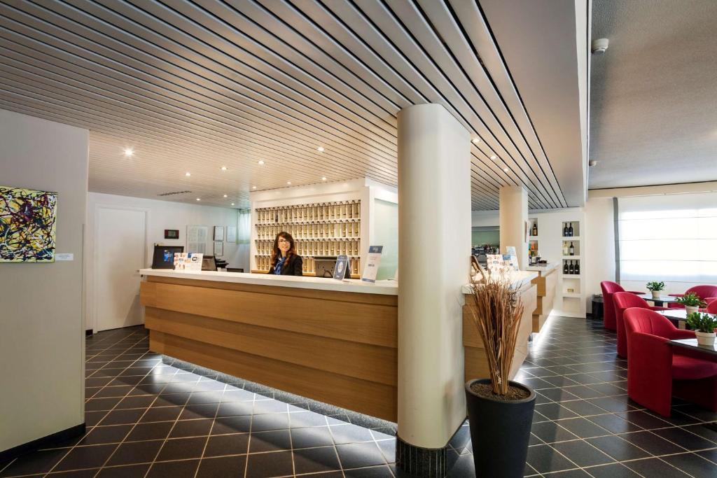 a woman standing at the counter of a restaurant at Best Western Hotel Residence Italia in Quartu SantʼElena