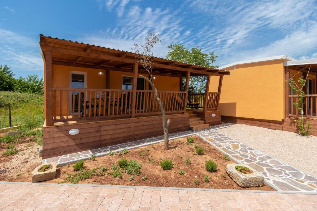 ein Haus mit einer Veranda mit einem Baum im Hof in der Unterkunft Mobile home Sea Turtle in Pašman