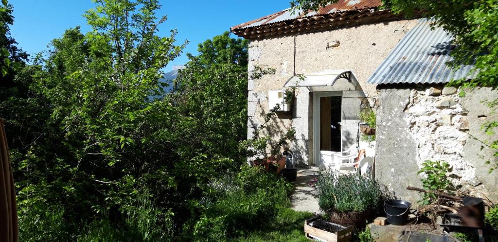 an old stone house with a chair in a yard at chez françoise in La Roche-des-Arnauds