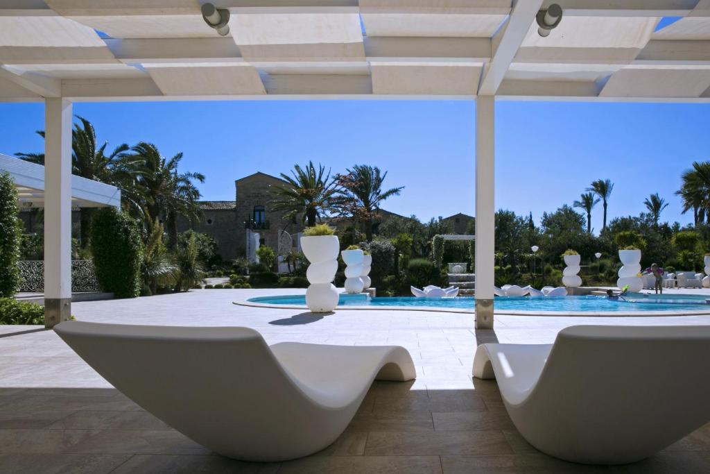 パルティニーコにあるOne bedroom apartement with shared pool furnished balcony and wifi at Partinico 6 km away from the beachのパティオ(白い椅子、スイミングプール付)