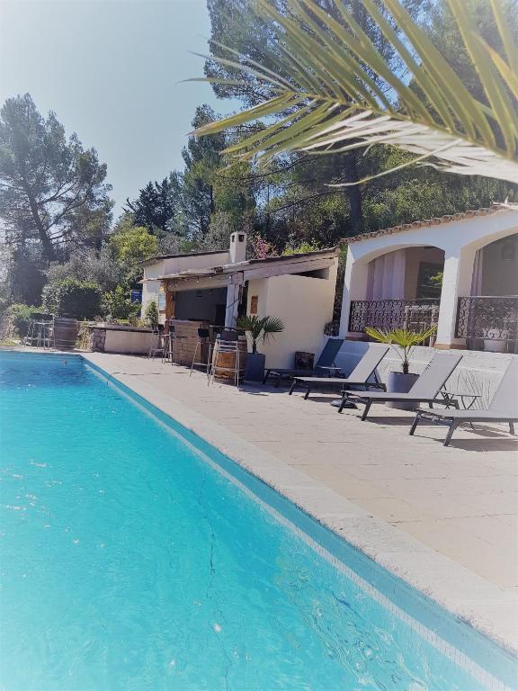 a swimming pool with chairs and a house at Villa Manoe in Draguignan