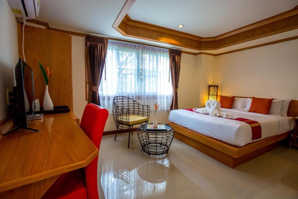 Dormitorio con cama, escritorio y TV en Phurua Inn ภูเรือ อินน์, en Loei