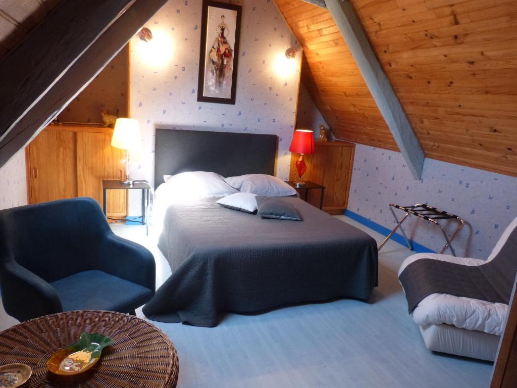 1 dormitorio con 1 cama y 1 silla azul en La Fermette du Rohiou, en Le Faouët