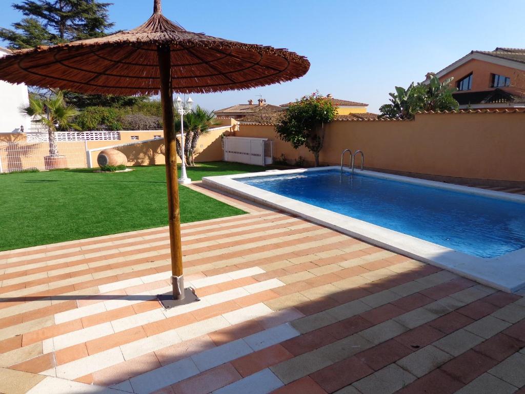 貝尼法約的住宿－4 bedrooms villa with sea view private pool and enclosed garden at Benifayo，游泳池旁的遮阳伞