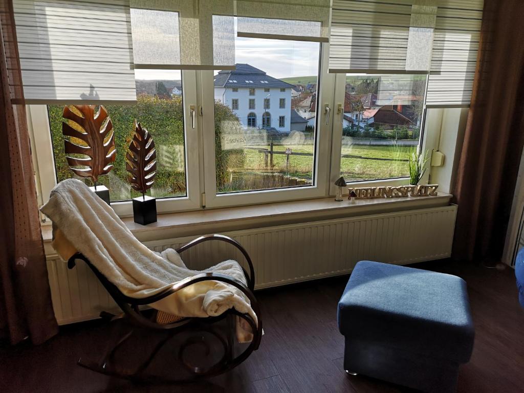 ein Wohnzimmer mit einem Stuhl und einem Fenster in der Unterkunft Ferienwohnungen "Am Berge" in Sachsenhausen