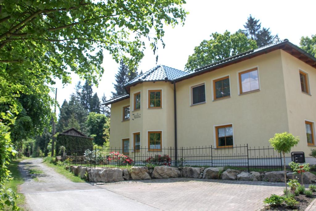 ein großes gelbes Haus mit einem Zaun davor in der Unterkunft Ferienwohnung Julia in Kurort Gohrisch