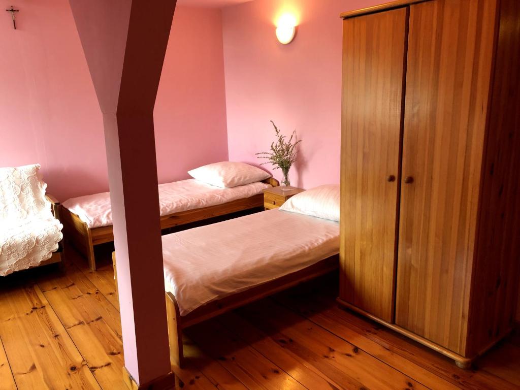 Rozogi的住宿－Gospodarstwo Agroturystyczne u Kubziniaka，配有粉红色墙壁和木地板的客房内的两张床