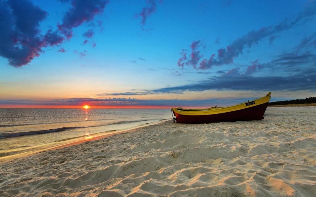 un barco sentado en la playa al atardecer en SeaLoft, en Grybivka