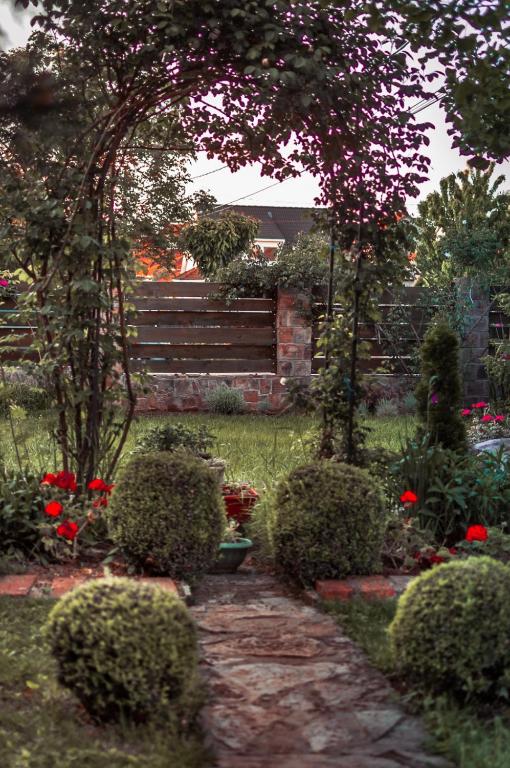 a garden with bushes and red flowers and a fence at Aerport - Natura Apartment in Belgrade