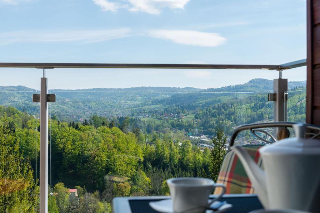 eine Tasse Kaffee auf einem Tisch vor einem Fenster in der Unterkunft Apartament Na Urlop - Wisła Bukowa Góra - Apartamenty z widokiem na panoramę Wisły in Wisła