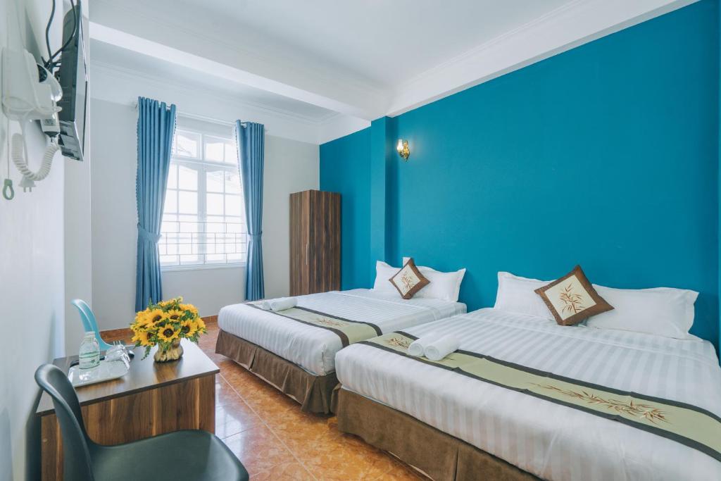 two beds in a room with blue walls at Khải Hoàng 2 in Da Lat