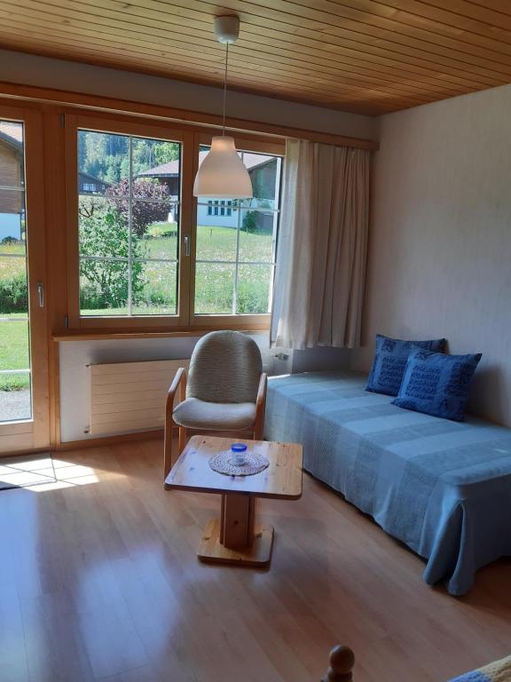 a bedroom with a bed and a chair and a table at Pension Alpina in Lenk