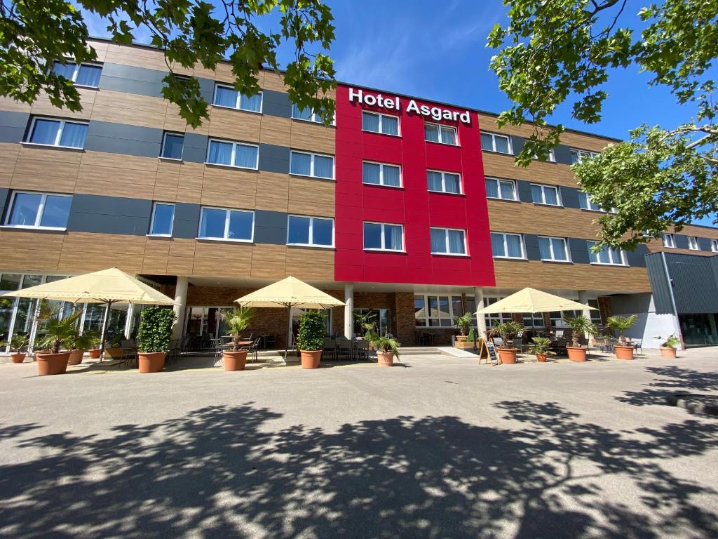 een hotelbuitenkant met een rood gebouw bij Hotel Asgard in Gersthofen