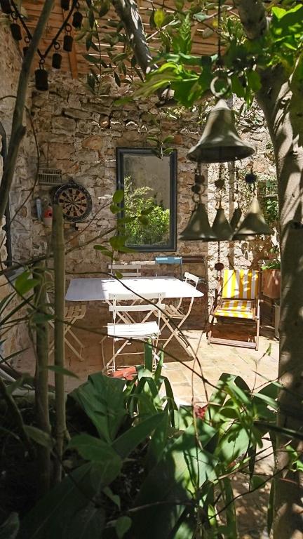 un patio avec une table et des chaises et un mur en pierre dans l'établissement La maison du brocanteur, à Aiguèze