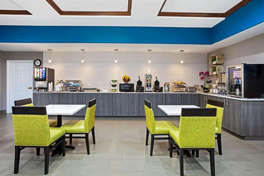 a restaurant with tables and yellow chairs and a counter at La Quinta by Wyndham Sulphur Springs in Sulphur Springs
