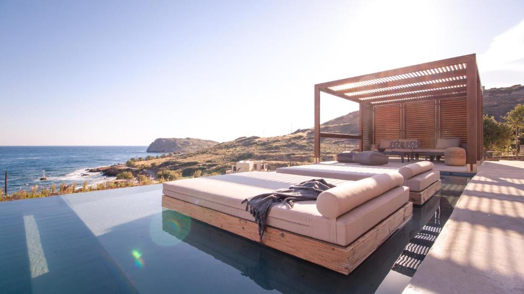 a bed sitting on top of a pool next to the ocean at Nuez Villas in Mochlos