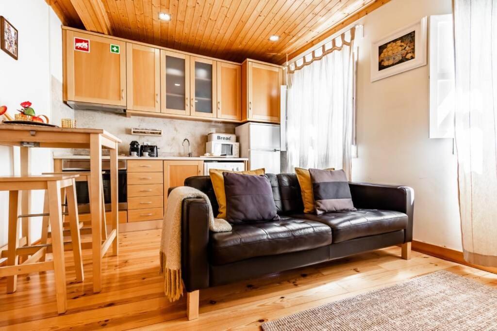 Una sala de estar con un sofá de cuero negro en una cocina. en Charming Duplex at Alfama, en Lisboa