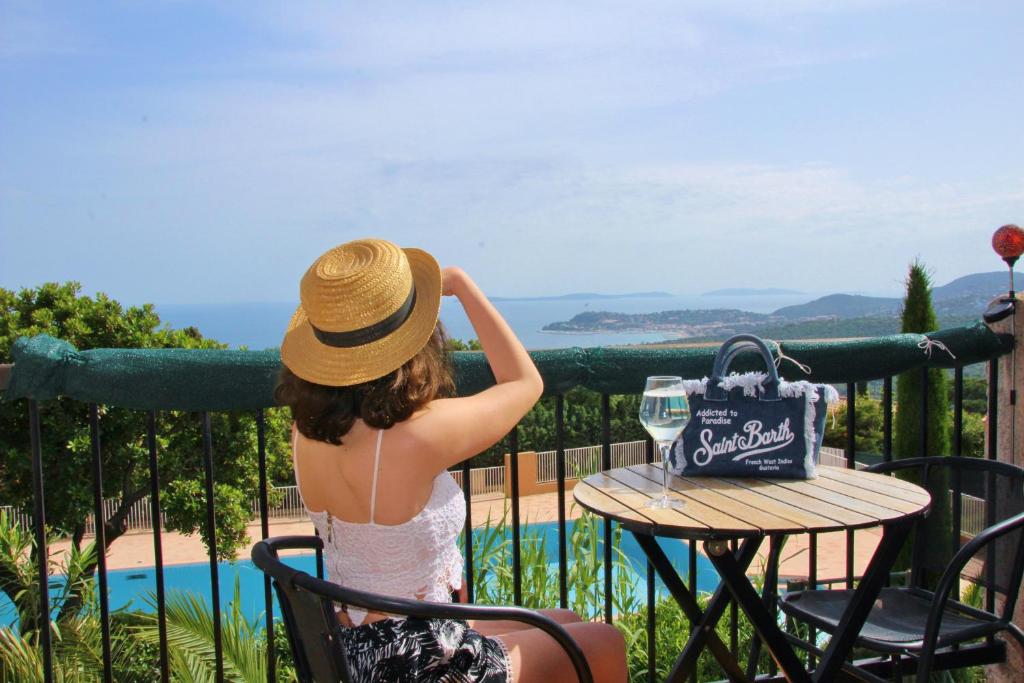 uma mulher de chapéu sentada à mesa com uma bolsa em STUDIO POOL HOUSE MDT 2 ETOILES VUE MER PANORAMIQUE AMAZING SEA VIEW WIFI LINGE LINEN INCLUT AIRCONDITIOn em La Croix-Valmer