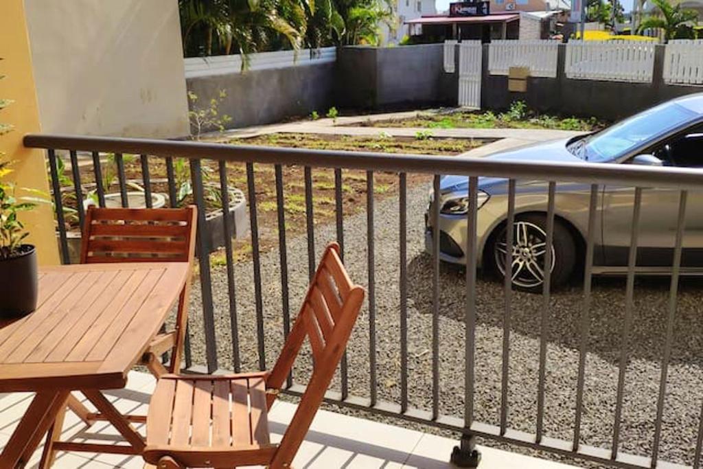 Una mesa y sillas en un balcón con un coche. en Appartement charmant à Saint Pierre 44 m² avec jardin clôturé, en Saint-Pierre
