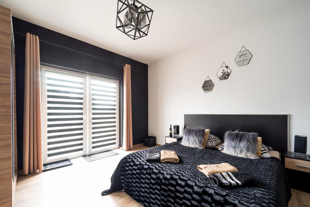 a bedroom with a black bed and a large window at Apartament Perła Pienin in Dębno