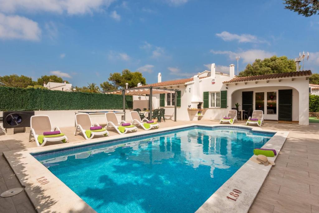 a swimming pool with chairs and a house at Villas Isi & Ana Mestral in Cala en Blanes