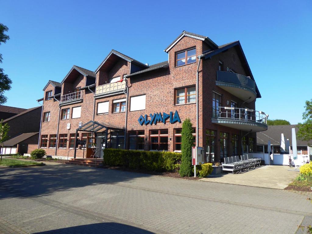 ein großes Backsteingebäude mit Balkon auf einer Straße in der Unterkunft Olympia Hotel & Restaurant in Inden