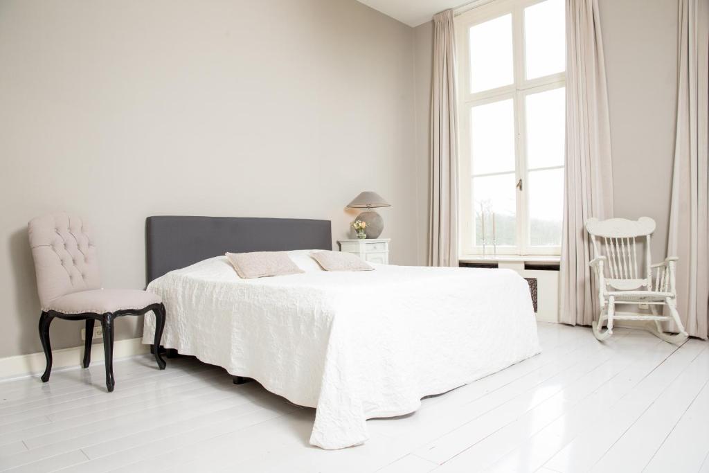 a white bedroom with a white bed and a chair at Hotel Kasteel Hoekelum in Bennekom