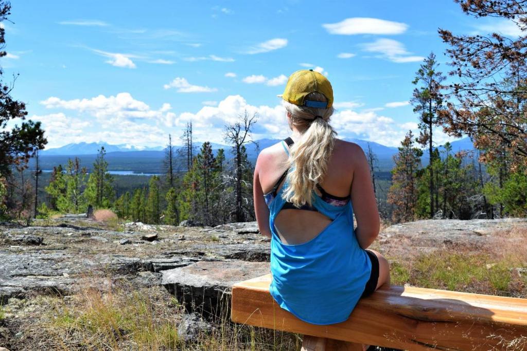 a woman in a blue dress sitting on a bench at Retreat Wilderness Inn in Nimpo Lake
