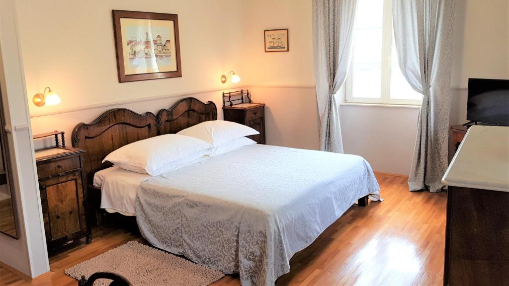 Un dormitorio con una cama con sábanas blancas y una ventana. en Villa Moretti, en Trogir