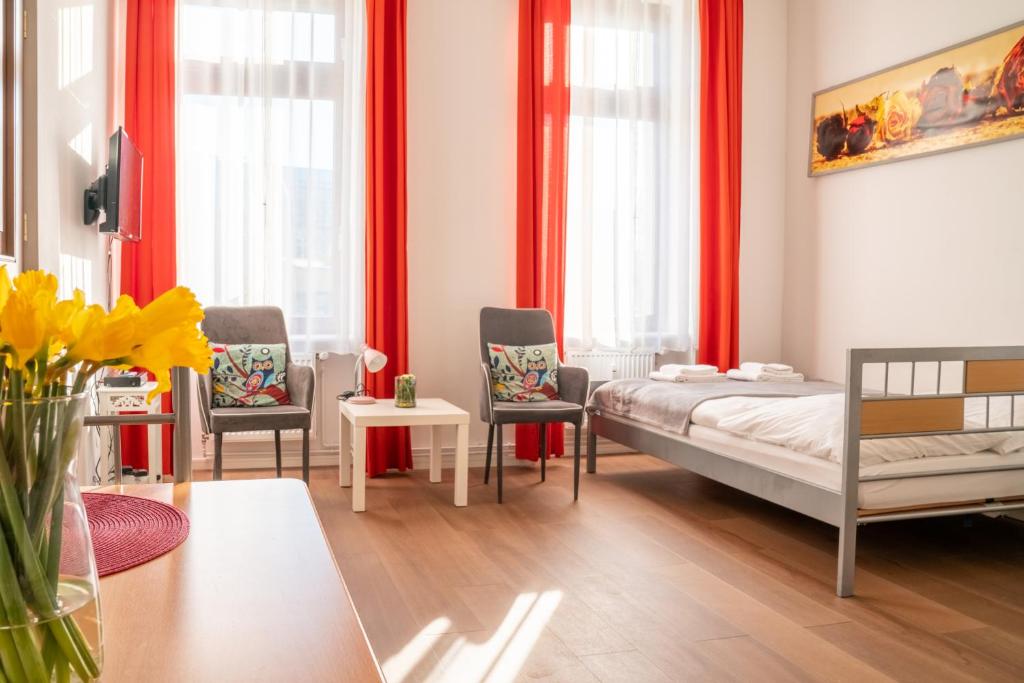 Schlafzimmer mit roten Vorhängen sowie einem Bett und Stühlen in der Unterkunft City Studio Apartment for 2, near Sonnenallee in Berlin