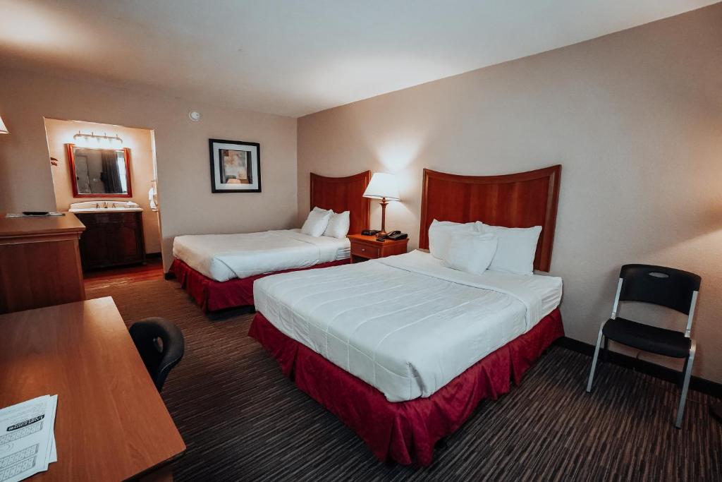 a hotel room with two beds and a desk at Lamplighter Inn and Suites - North in Springfield