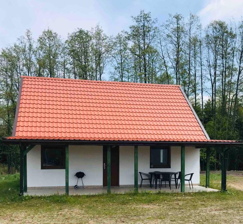 a house with an orange roof with a table and chairs at Domki Marina Niedźwiedzi Róg in Ruciane-Nida