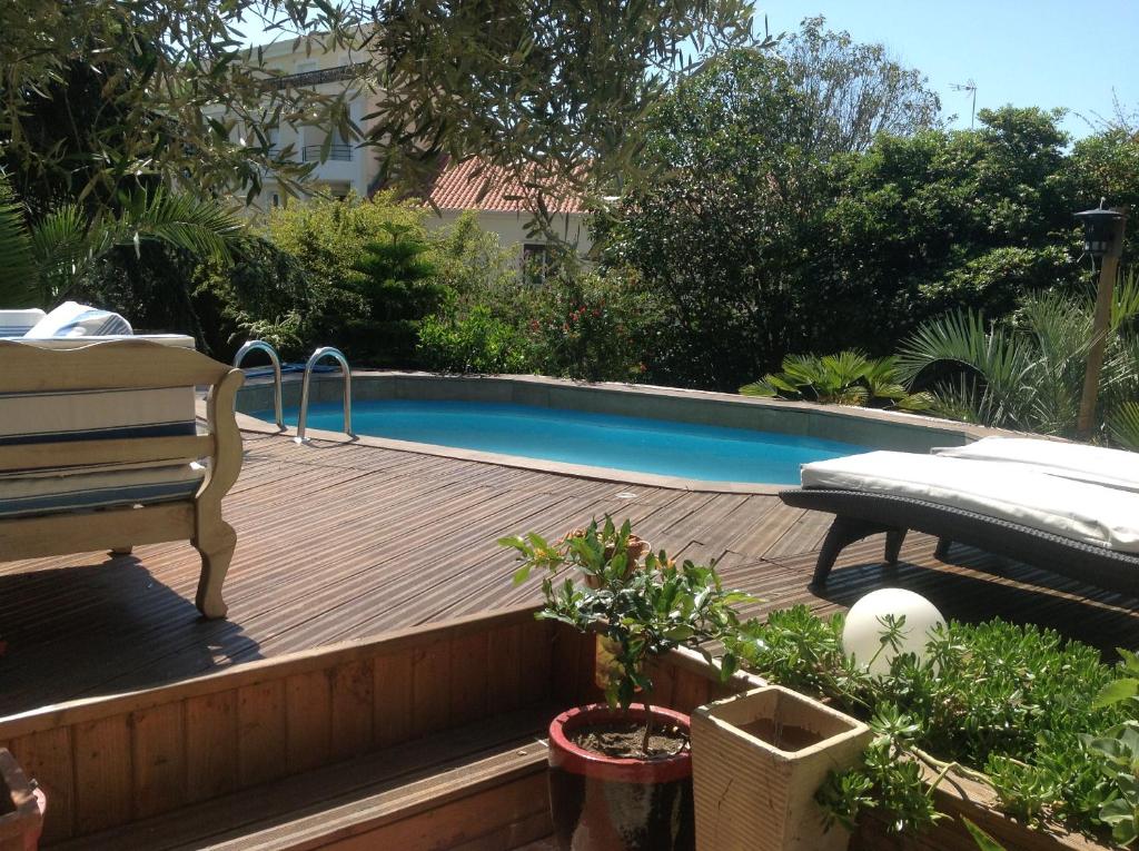 a wooden deck with a swimming pool in a yard at A l'ombre du cedre in Hyères