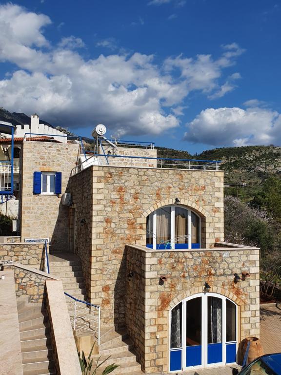 a stone house with blue windows and stairs at Neohori 3 in Stoupa