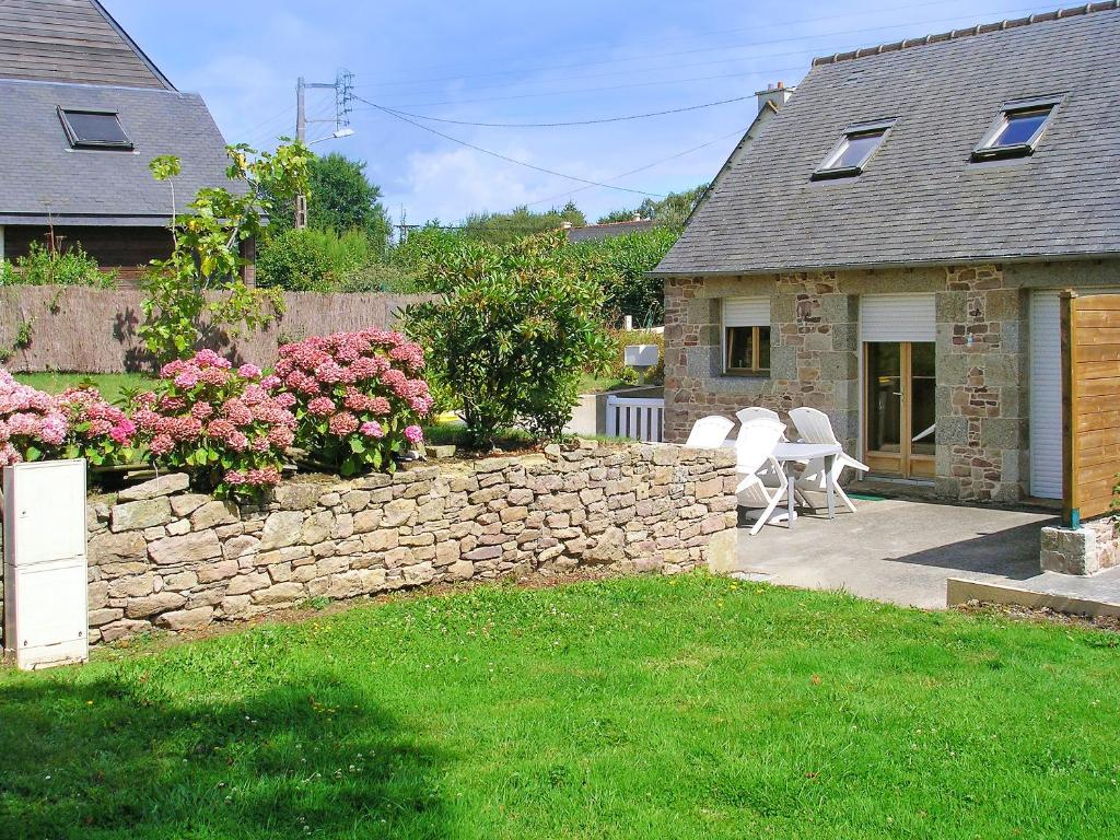 a house with a stone wall and a table and chairs at Maison accueillante à Plehedel avec jardin et parking privé in Pléhédel