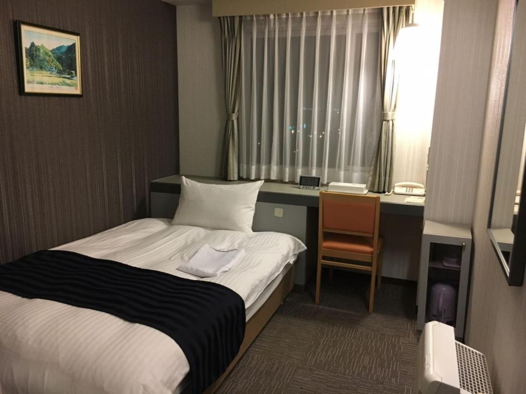 a small hotel room with a bed and a desk at Tottori City Hotel / Vacation STAY 81356 in Tottori