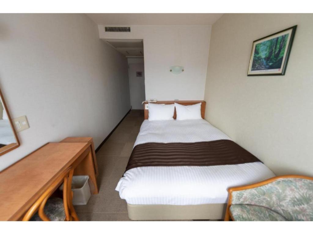 Tottori City Hotel / Vacation STAY 81348 في توتوري: غرفة صغيرة بها سريرين مع مكتب
