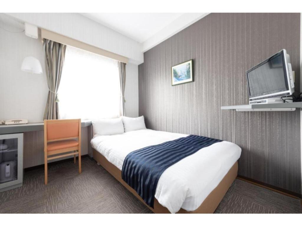 a hotel room with a bed and a flat screen tv at Tottori City Hotel / Vacation STAY 81354 in Tottori