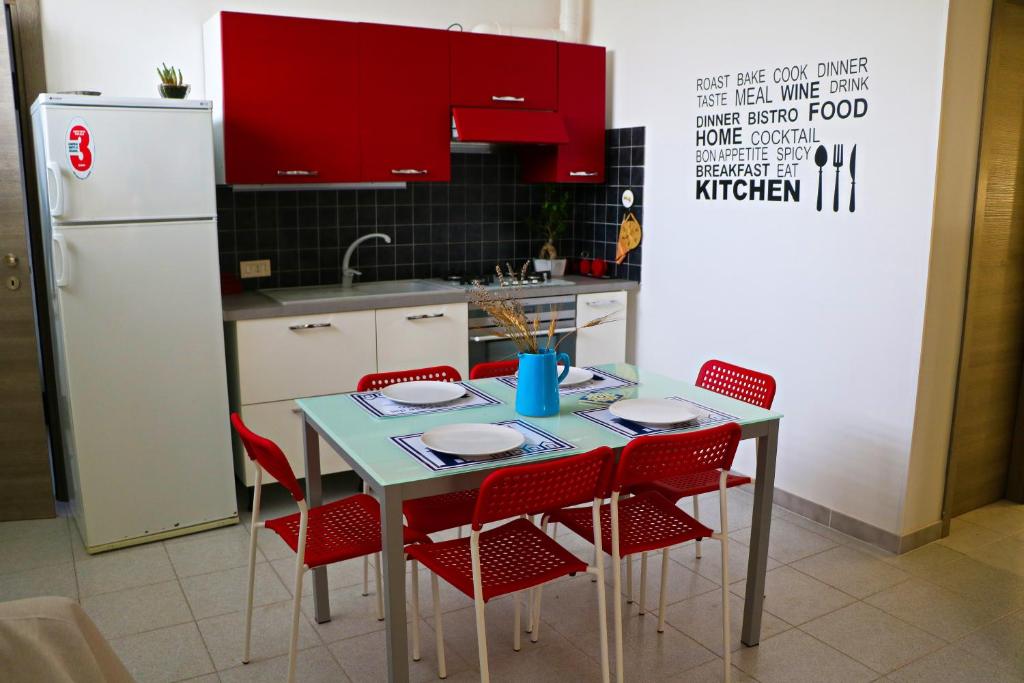 eine Küche mit einem Tisch mit roten Stühlen und einem Kühlschrank in der Unterkunft Le Case del Vento - APPARTAMENTO MAESTRALE in Torre Canne