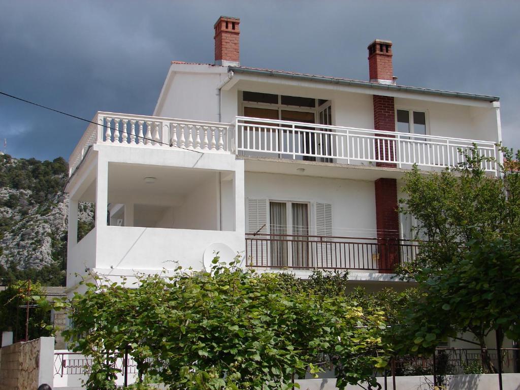 a white house with a balcony and trees at Apartments Curin in Hvar