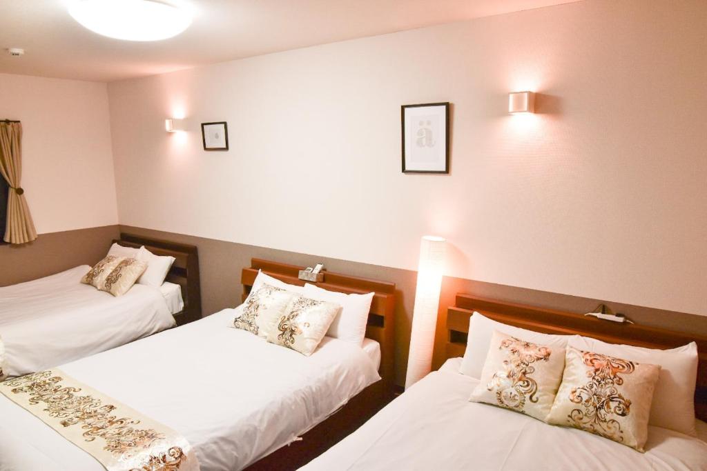 2 łóżka w pokoju z białą pościelą i poduszkami w obiekcie Kyoto Minami-ku - House / Vacation STAY 81714 w mieście Kioto
