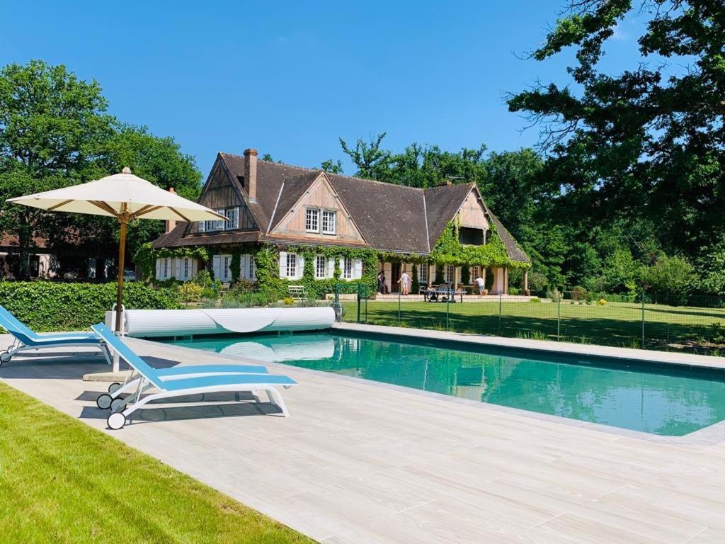 a house with a swimming pool with two chairs and an umbrella at Les Vieux Guays in Cerdon